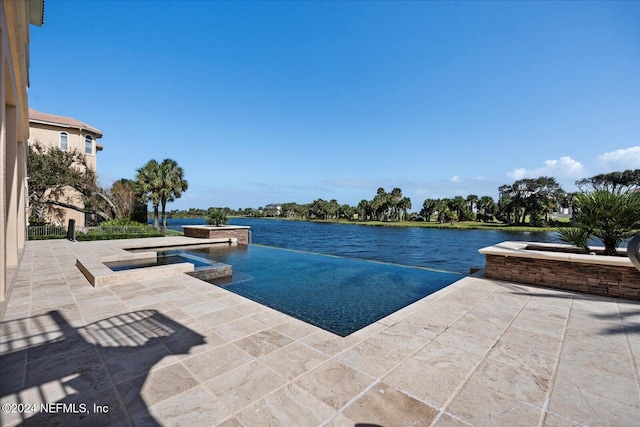 view of swimming pool featuring a patio, a water view, and an in ground hot tub