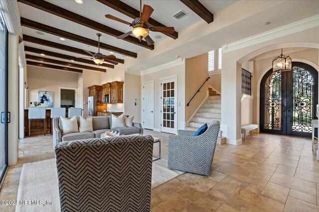 living room with french doors, ornamental molding, light tile patterned floors, beam ceiling, and ceiling fan