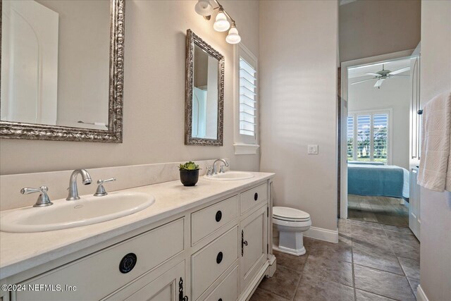 bathroom with toilet, vanity, ceiling fan, and tile patterned floors