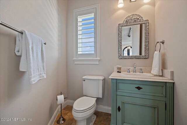 bathroom with toilet, vanity, and tile patterned floors