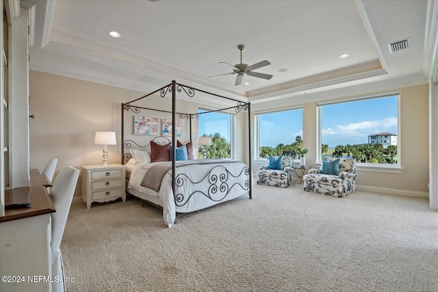 bedroom featuring ornamental molding, ceiling fan, a textured ceiling, a raised ceiling, and carpet floors