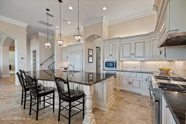 kitchen with built in appliances, ornamental molding, a kitchen breakfast bar, decorative light fixtures, and a large island