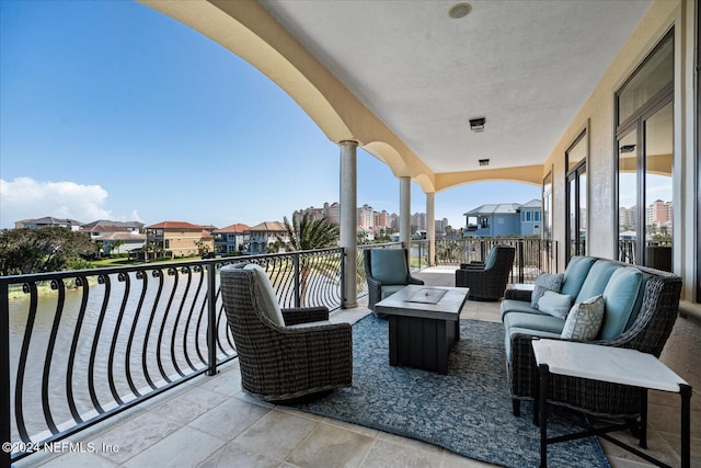 view of patio featuring a balcony and an outdoor living space with a fire pit