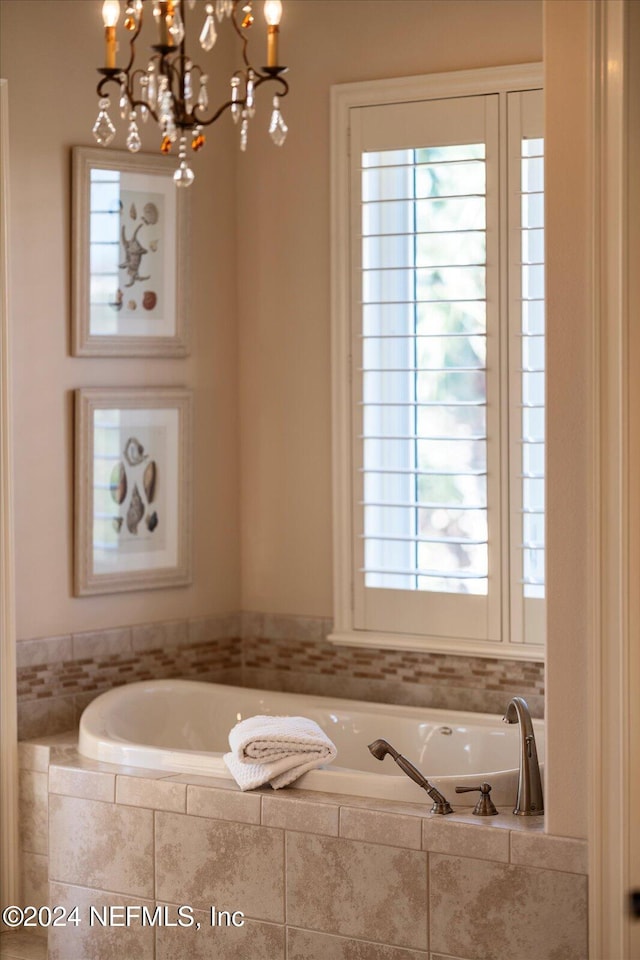 bathroom featuring tiled tub and a chandelier