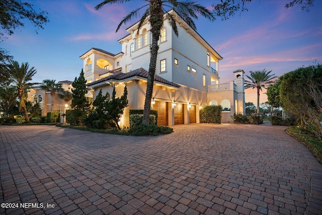 property exterior at dusk with a garage and a balcony