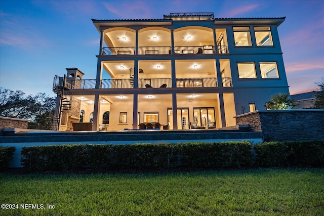 back house at dusk featuring a patio and a balcony