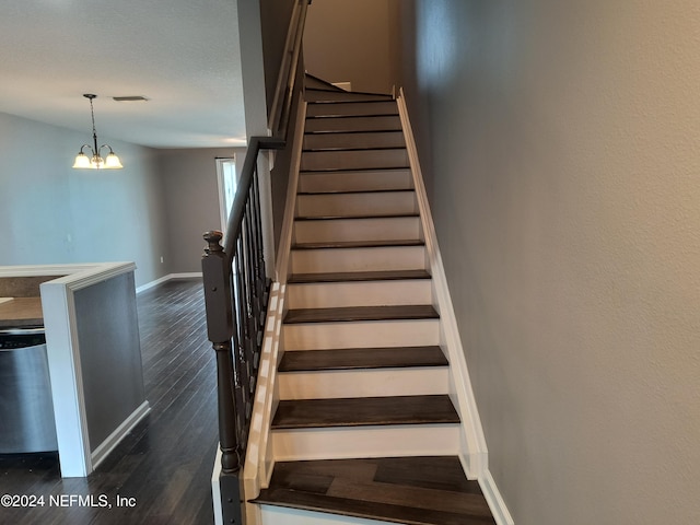 stairway with hardwood / wood-style floors and an inviting chandelier