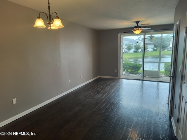 spare room with ceiling fan with notable chandelier, dark hardwood / wood-style flooring, and a water view