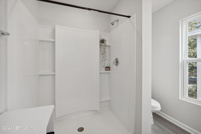 bathroom featuring tiled shower, hardwood / wood-style floors, and toilet