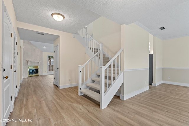 stairway featuring a tiled fireplace, visible vents, and wood finished floors