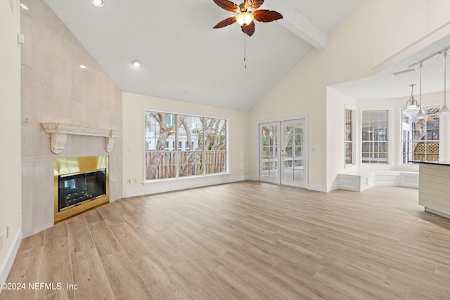 unfurnished living room featuring high vaulted ceiling, beamed ceiling, a fireplace, and light wood-style floors