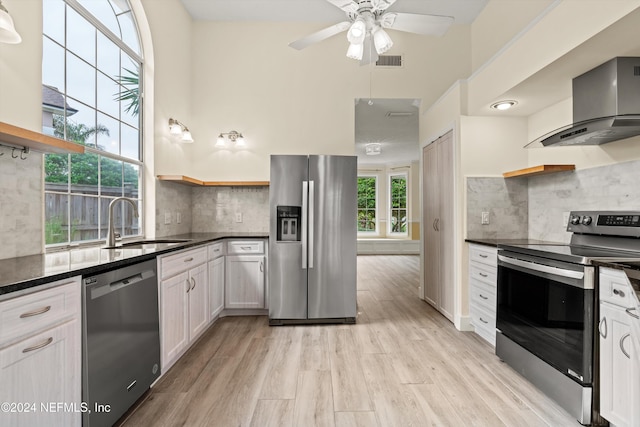 kitchen with wall chimney exhaust hood, appliances with stainless steel finishes, white cabinetry, open shelves, and a sink