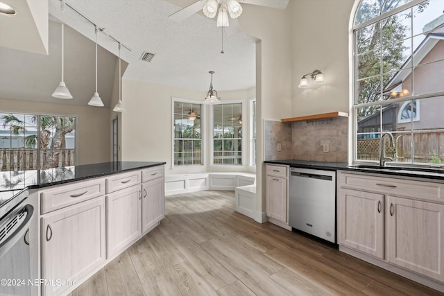 kitchen featuring stainless steel appliances, a sink, visible vents, light wood finished floors, and decorative light fixtures