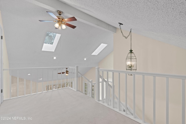 interior space with a textured ceiling, vaulted ceiling with skylight, carpet floors, and ceiling fan