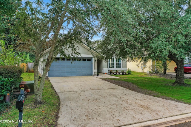 view of property hidden behind natural elements featuring a front yard and a garage