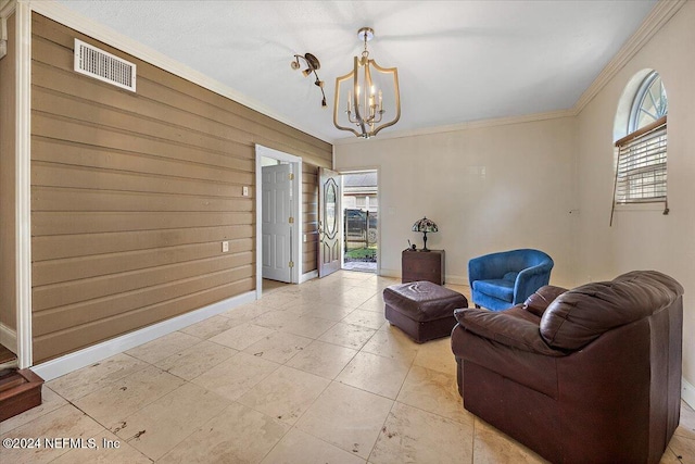 sitting room featuring a chandelier, wooden walls, plenty of natural light, and ornamental molding