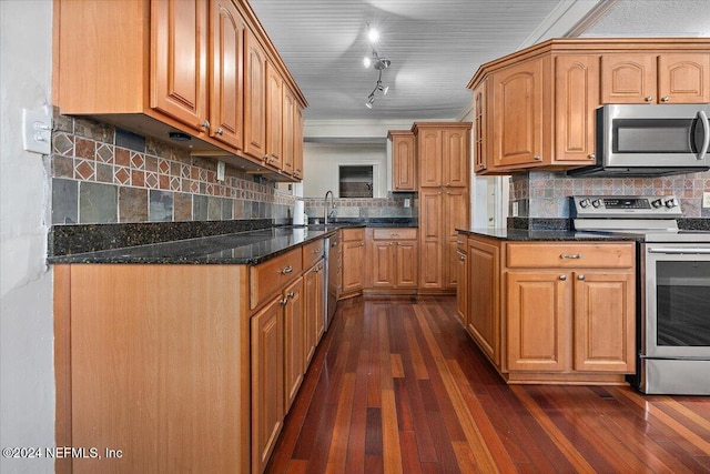 kitchen with sink, stainless steel appliances, dark hardwood / wood-style floors, and dark stone countertops