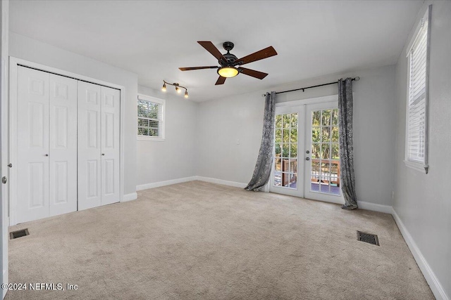 unfurnished bedroom with multiple windows, ceiling fan, french doors, and light carpet