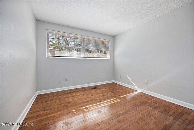 unfurnished room with wood-type flooring and a textured ceiling