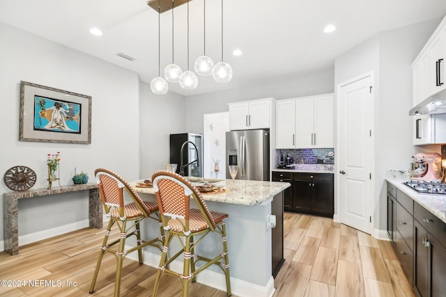 kitchen with a center island with sink, white cabinets, appliances with stainless steel finishes, and light hardwood / wood-style flooring