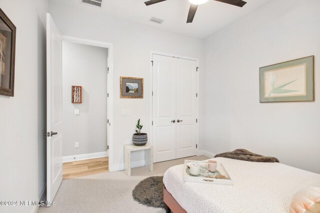 bedroom with ceiling fan, light colored carpet, and a closet