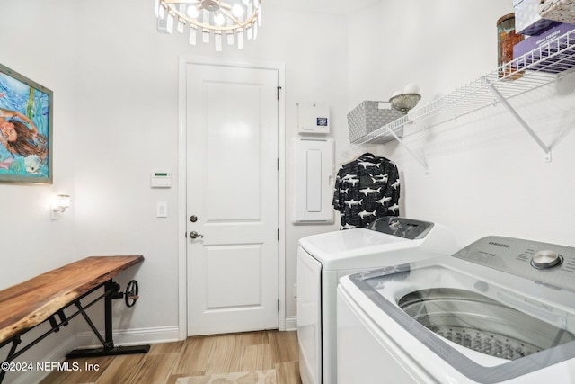 washroom with washing machine and clothes dryer, a chandelier, and light wood-type flooring