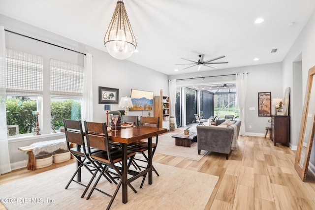 dining space featuring ceiling fan with notable chandelier and light wood-type flooring