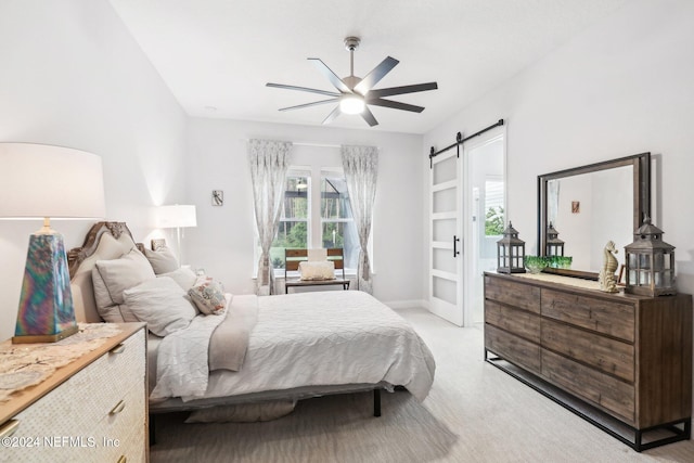 carpeted bedroom featuring a barn door and ceiling fan