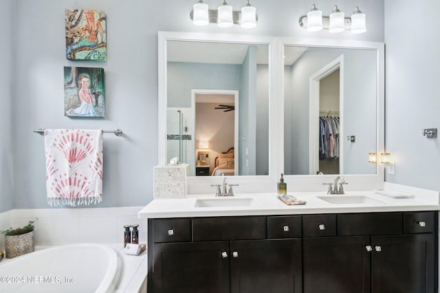 bathroom with vanity, ceiling fan, and tiled tub