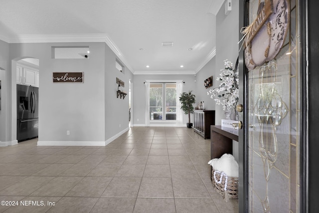 foyer with light tile patterned floors and crown molding