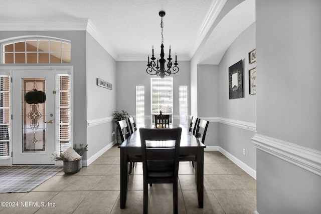 tiled dining room with ornamental molding, a textured ceiling, and a chandelier