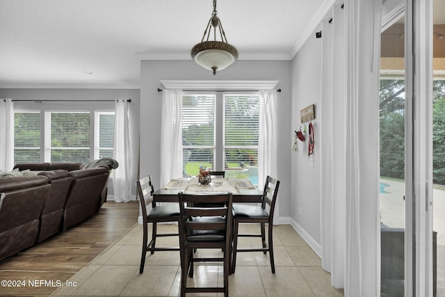 dining area with a textured ceiling, crown molding, and light hardwood / wood-style flooring