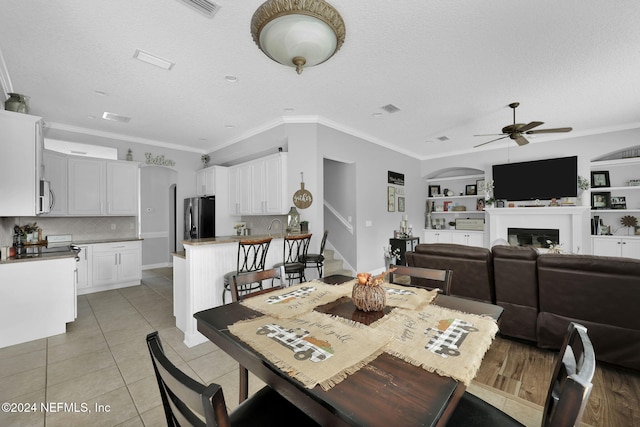 dining room with a textured ceiling, ceiling fan, built in features, and ornamental molding