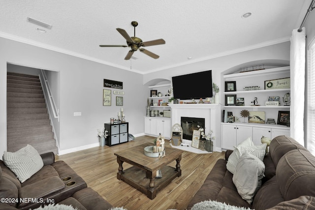 living room with a textured ceiling, light hardwood / wood-style flooring, ceiling fan, and crown molding