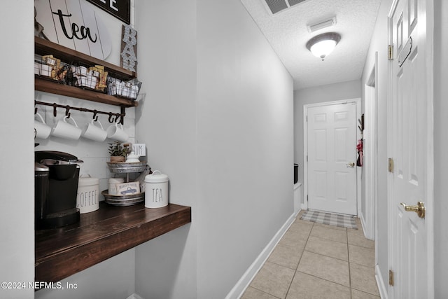 hallway with light tile patterned floors and a textured ceiling