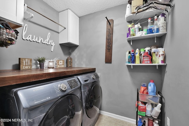 washroom featuring washer and clothes dryer, cabinets, and a textured ceiling