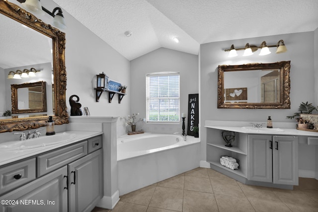 bathroom with vanity, lofted ceiling, a bath, tile patterned floors, and a textured ceiling