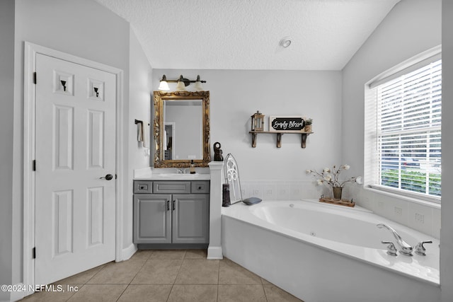 bathroom with a washtub, tile patterned floors, lofted ceiling, a textured ceiling, and vanity