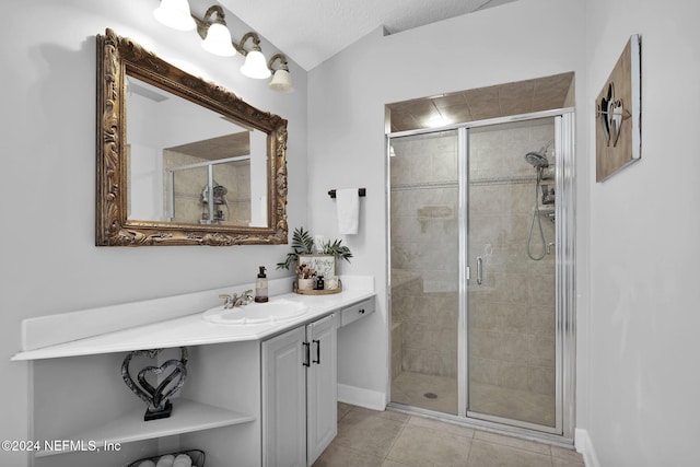 bathroom with a textured ceiling, vanity, tile patterned floors, and a shower with door