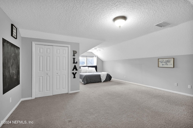 carpeted bedroom featuring a textured ceiling, vaulted ceiling, and a closet