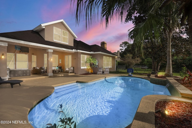 pool at dusk featuring a patio area