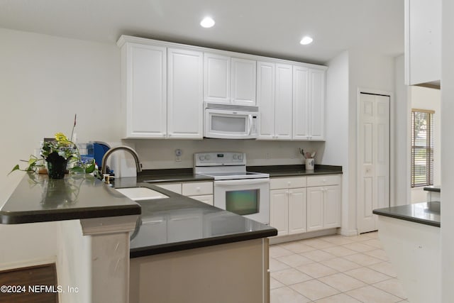 kitchen with white appliances, a peninsula, a sink, dark countertops, and recessed lighting