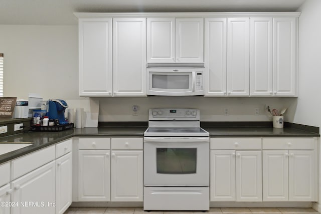 kitchen with white appliances, dark countertops, and white cabinetry