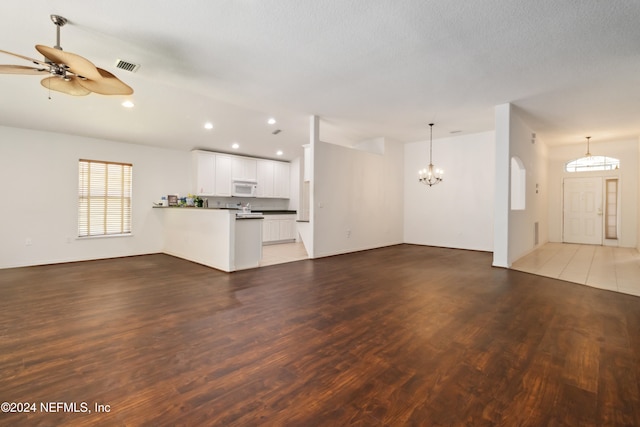 unfurnished living room featuring a textured ceiling, dark hardwood / wood-style floors, and ceiling fan with notable chandelier