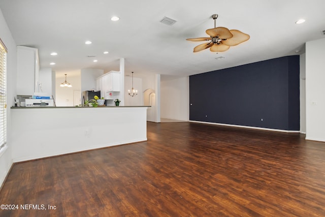 unfurnished living room featuring ceiling fan with notable chandelier and dark hardwood / wood-style floors