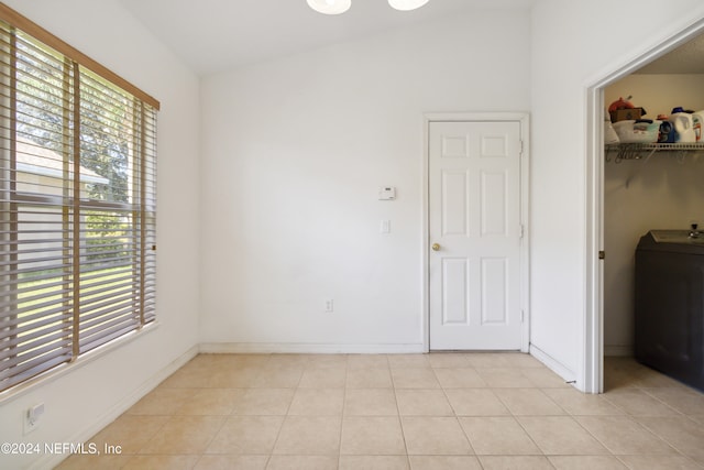 unfurnished room featuring light tile patterned floors, vaulted ceiling, and washer / dryer