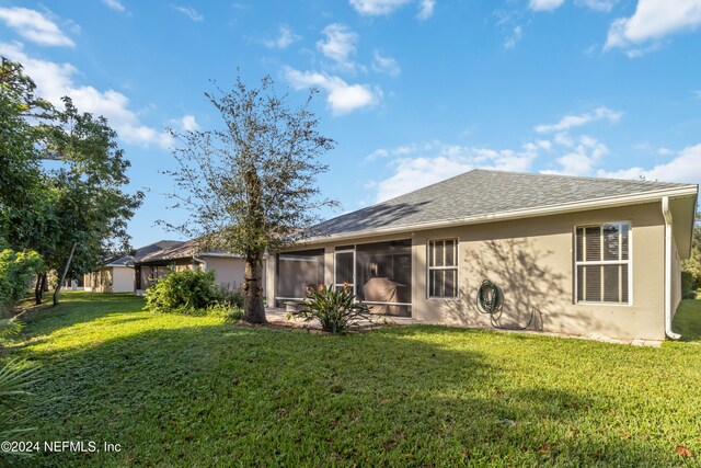 back of property featuring a lawn and a sunroom