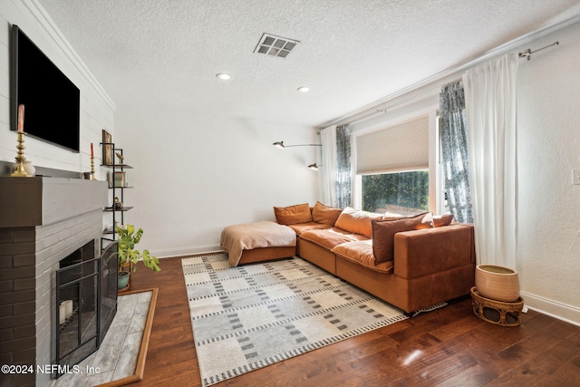 living room featuring a fireplace, hardwood / wood-style floors, a textured ceiling, and ornamental molding