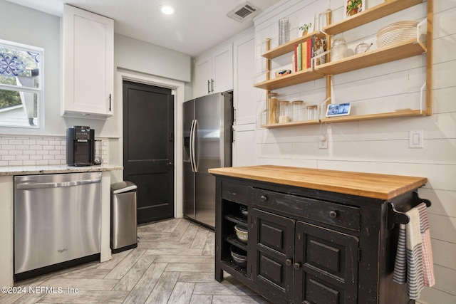 kitchen with tasteful backsplash, butcher block counters, white cabinetry, and appliances with stainless steel finishes