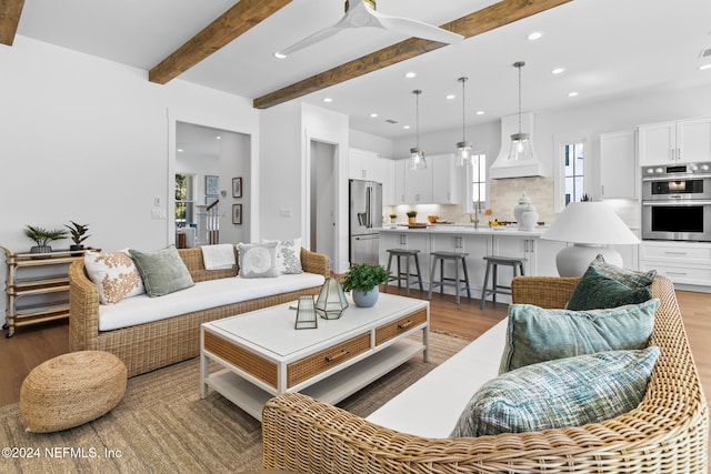 living room featuring a wealth of natural light, hardwood / wood-style floors, beamed ceiling, and ceiling fan